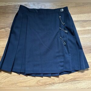 Woman’s Black pleated mini skirt with large safety pins closures